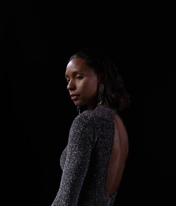 Woman in a calm yoga pose in a dark studio with coral accents.